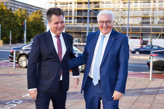 Jürgen Dusel und Hubertus Heil stehen nebeneinander und begrüßen sich. Sie stehen an einer Straße. Im Hintergrund sieht man Autos und zwei Häuser. (Quelle: Anna Spindelndreier) Jürgen Dusel und Hubertus Heil stehen nebeneinander und begrüßen sich. Sie stehen an einer Straße. Im Hintergrund sieht man Autos und zwei Häuser.