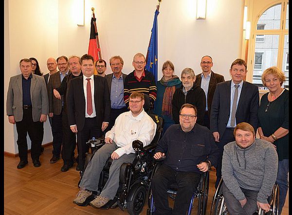 Abgebildet sind neben Herrn Dusel die Vertreterinnen und Vertreter der Mitgliedsorganisationen des Inklusionsbeirates der 19. Legislaturperiode. Im Hintergrund sind die Deutschland- und die Europafahne aufgestellt.