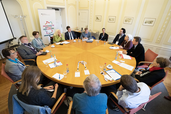 Zu sehen sind einige Personen, die um einen runden Tisch sitzen und reden. Auf dem Tisch liegen Unterlagen. (Quelle: Behindertenbeauftragter/Dirk Enters ) Zu sehen sind einige Personen, die um einen runden Tisch sitzen und reden. Auf dem Tisch liegen Unterlagen.
