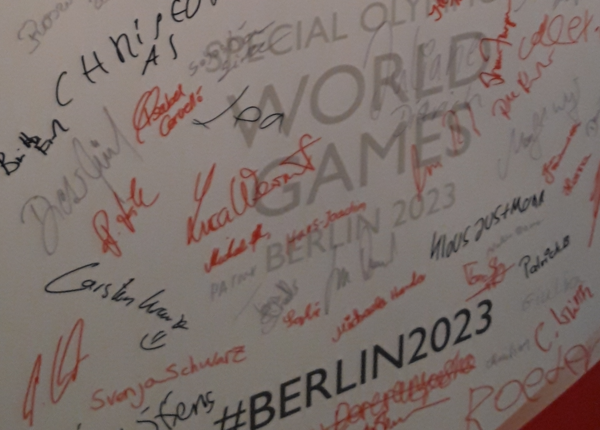 Zu sehen ist eine Wand mit zahlreichen Unterschriften und dem Hashtag #Berlin2023