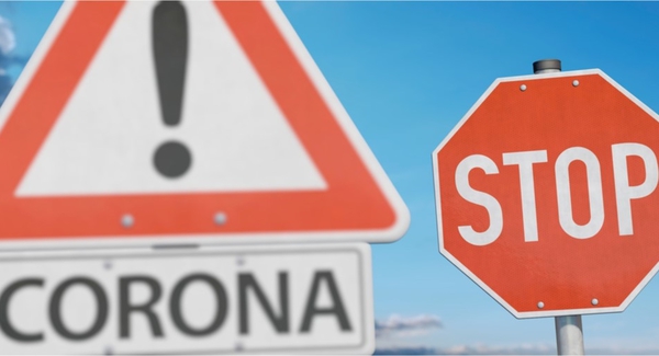 Zwei Straßenverkehrszeichen. Links ein Warnschild mit Ausrufezeichen, darunter ein Schild, auf dem „Corona“ steht. Rechts ein Stopschild.
