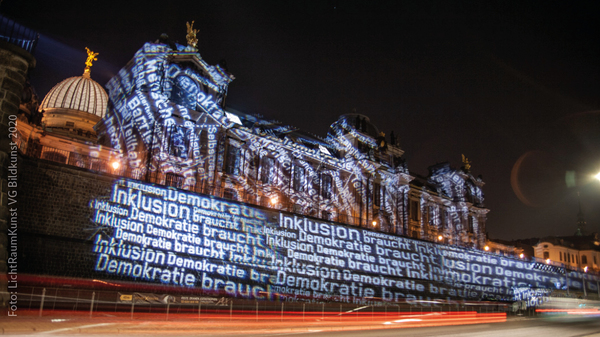 Die Fassade der Hochschule der Bildende Künste und die Mauer an der Brühlschem Terrasse werden angestrahlt mit verschiedenen Begriffen wie „Inklusion“ und „Teilhabe“. Außerdem das Motto „Demokratie braucht Inklusion“.