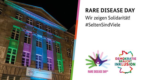 Grafik mit einem Foto des Kleisthauses, Dienstsitz des Beauftragten, das in den Farben grün, pink und blau erleuchtet ist. Daneben die Überschrift: Rare Disease Day, Wir zeigen Solidarität! 