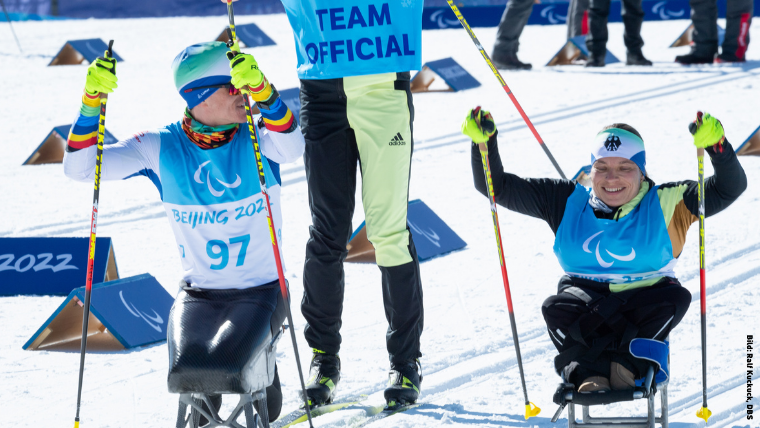 Athlet*innen und Assistenz beim Ski-Langlauf sitzend.