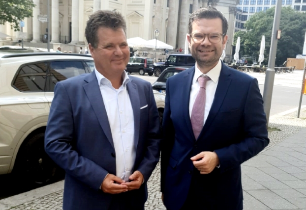 Jürgen Dusel und Marco Buschmann stehen nebeneinander auf einer Straße und lächeln in die Kamera.